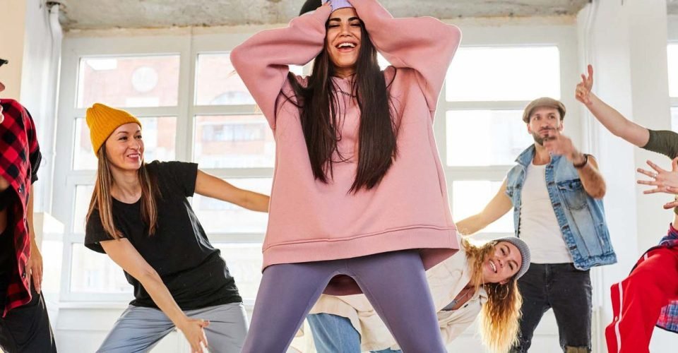 woman learning hip-hop choreography with her groupmates in dance studio, choreography concept
